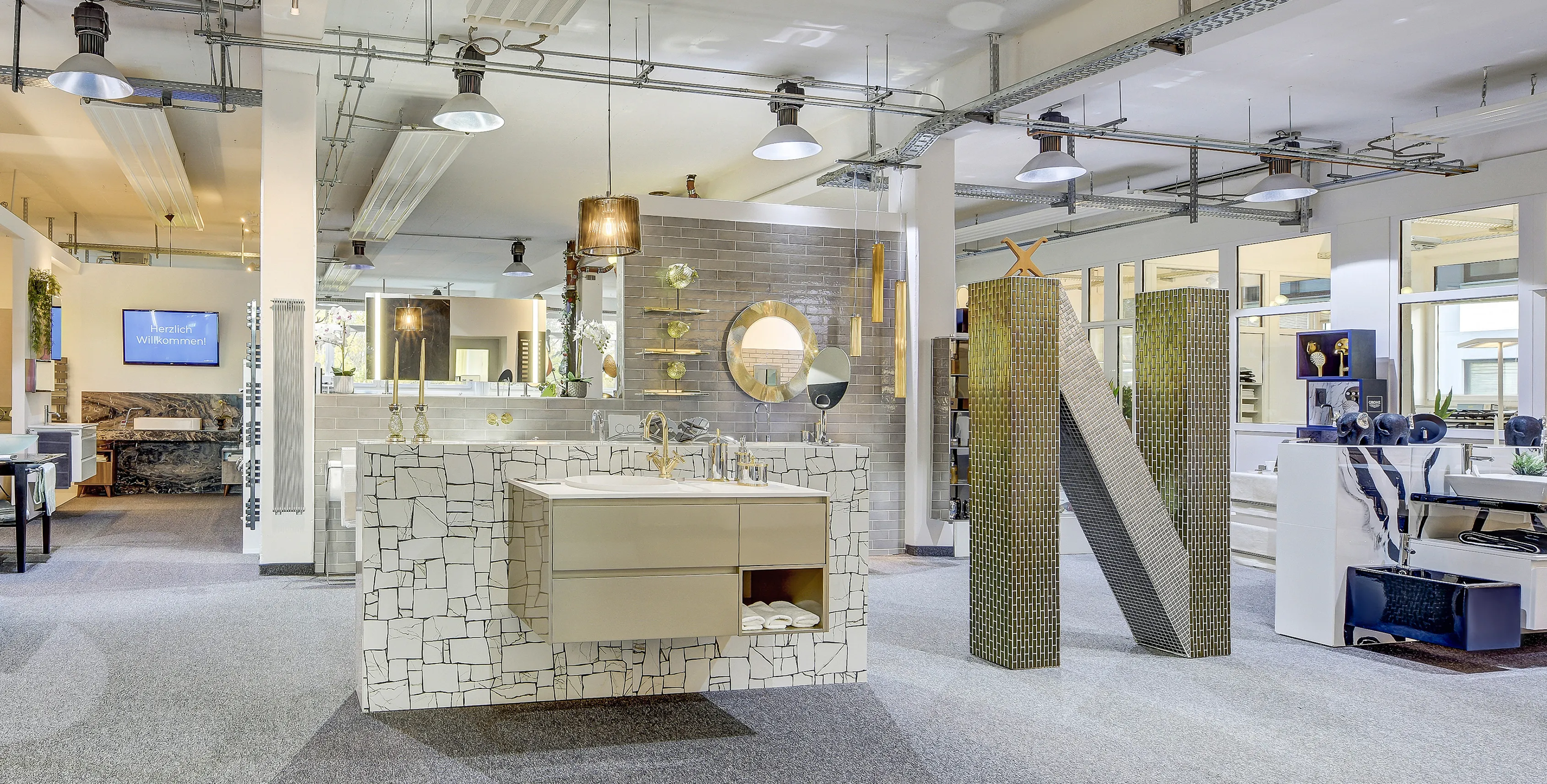 Ein stilvoll gestalteter Ausstellungsbereich in Düsseldorf der Nessmann bad & heizung GmbH mit einem modernen Waschtisch, goldenen Armaturen und dekorativen Fliesen in einem eleganten Design.