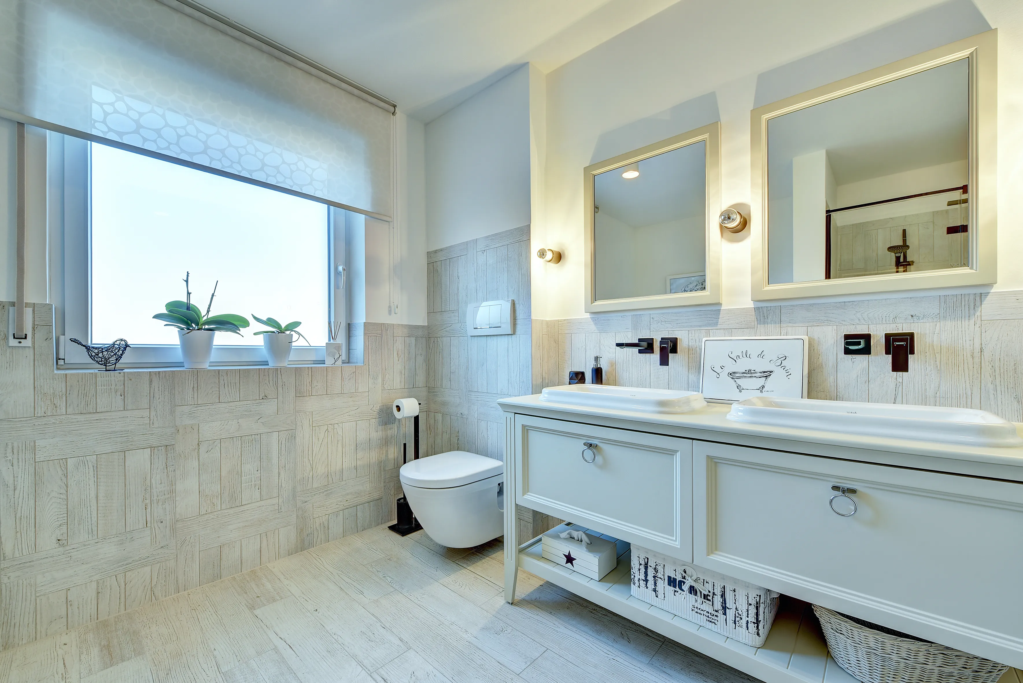 Detailansicht des Waschtischbereichs mit Doppelbecken, Wandarmaturen und Fensterlicht, realisiert durch die Nessmann Bad & Heizung GmbH.