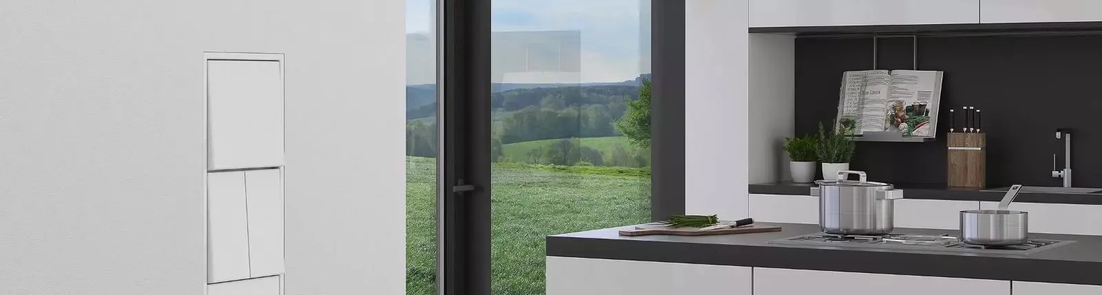 Moderner Unterputz-Lichtschalter in Weiß an der Wand neben offener Designküche mit Blick ins Grüne.