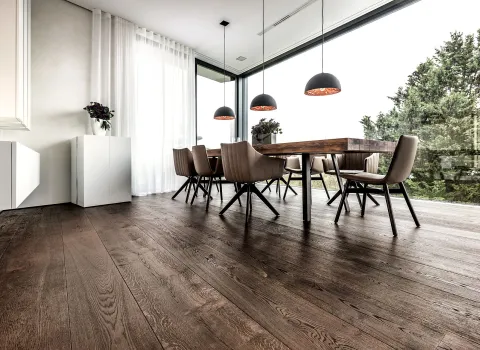 Wohnbereich mit Pendellampen, Holzboden und Holztisch.