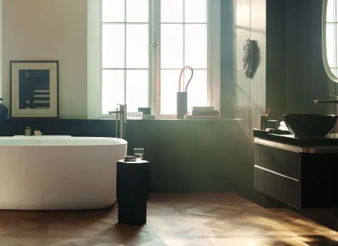 Elegantes Badezimmer mit freistehender Badewanne, großen Fenstern und stilvollen Accessoires wie Vasen und Büchern.