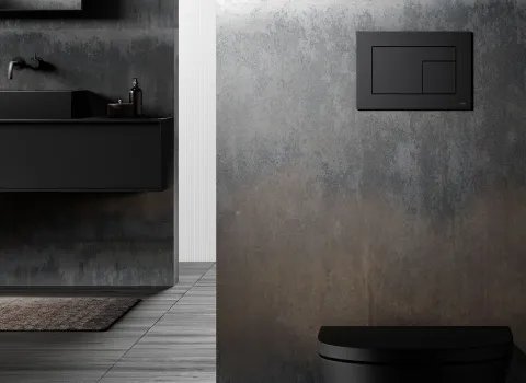 In einem Badezimmer mit rostig-industrieller Wandoptik ist eine schwarze TECEvelvet WC-Betätigungsplatte installiert.