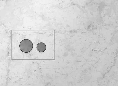 ine TECEloop WC-Betätigungsplatte mit zwei unterschiedlich großen, runden Druckknöpfen aus Metall ist nahtlos in eine helle Marmorwand eingelassen.