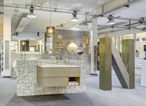 Ein stilvoll gestalteter Ausstellungsbereich in Düsseldorf der Nessmann bad & heizung GmbH mit einem modernen Waschtisch, goldenen Armaturen und dekorativen Fliesen in einem eleganten Design.