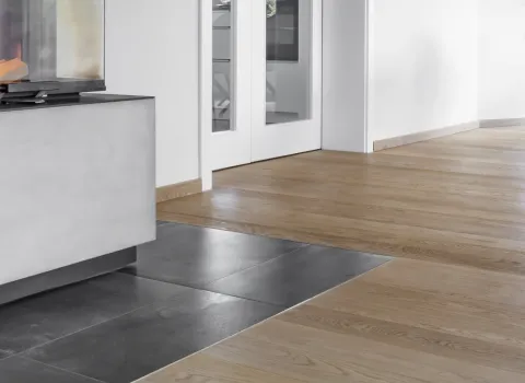 Ein modernes Wohnzimmer mit hellem Echtholzparkett und einem stilvollen, eckigen Kamin mit Glasfront.