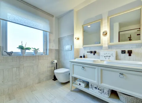 Detailansicht des Waschtischbereichs mit Doppelbecken, Wandarmaturen und Fensterlicht, realisiert durch die Nessmann Bad & Heizung GmbH.