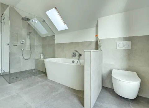Badansicht mit freistehender Badewanne, separater Glasdusche und wandhängendem WC, ausgeführt von der Nessmann Bad & Heizung GmbH.