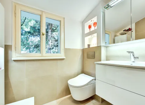 Helles Bad mit wandhängendem WC, Waschtischunterschrank und Fensterblick ins Grüne, realisiert von der Nessmann Bad & Heizung GmbH.
