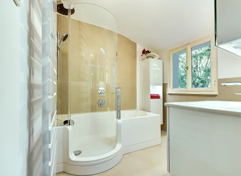 Teilansicht eines Badezimmers mit Badewanne, Waschtisch und Fenster für natürliche Belichtung, ausgeführt von der Nessmann Bad & Heizung GmbH.