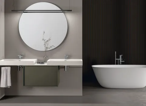 Zeitloses Badezimmer von Stocco mit Doppelwaschtisch, rundem Spiegel, grüner Mittelkonsole und freistehender Badewanne.