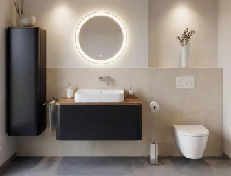 Badezimmer mit haengendem Aufsatz-Waschtisch, ovalem Leuchtspiegel und wandhaengendem Hochschrank.