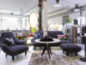 Ein gemütlicher Loungebereich mit dunkelgrauen Sesseln, einem runden Tisch und dekorativen Leuchten, ausgestellt in der Badausstellung in Düsseldorf der Nessmann bad & heizung GmbH.