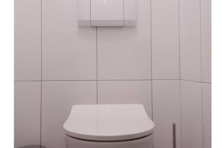 Weiße Toilette im weißgefliesten Bad