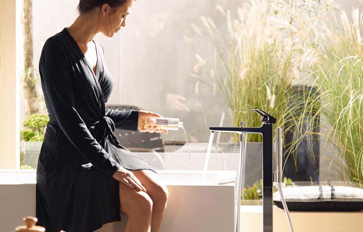 Frau sitzt auf Wannenrand und betätigt Wannenarmatur